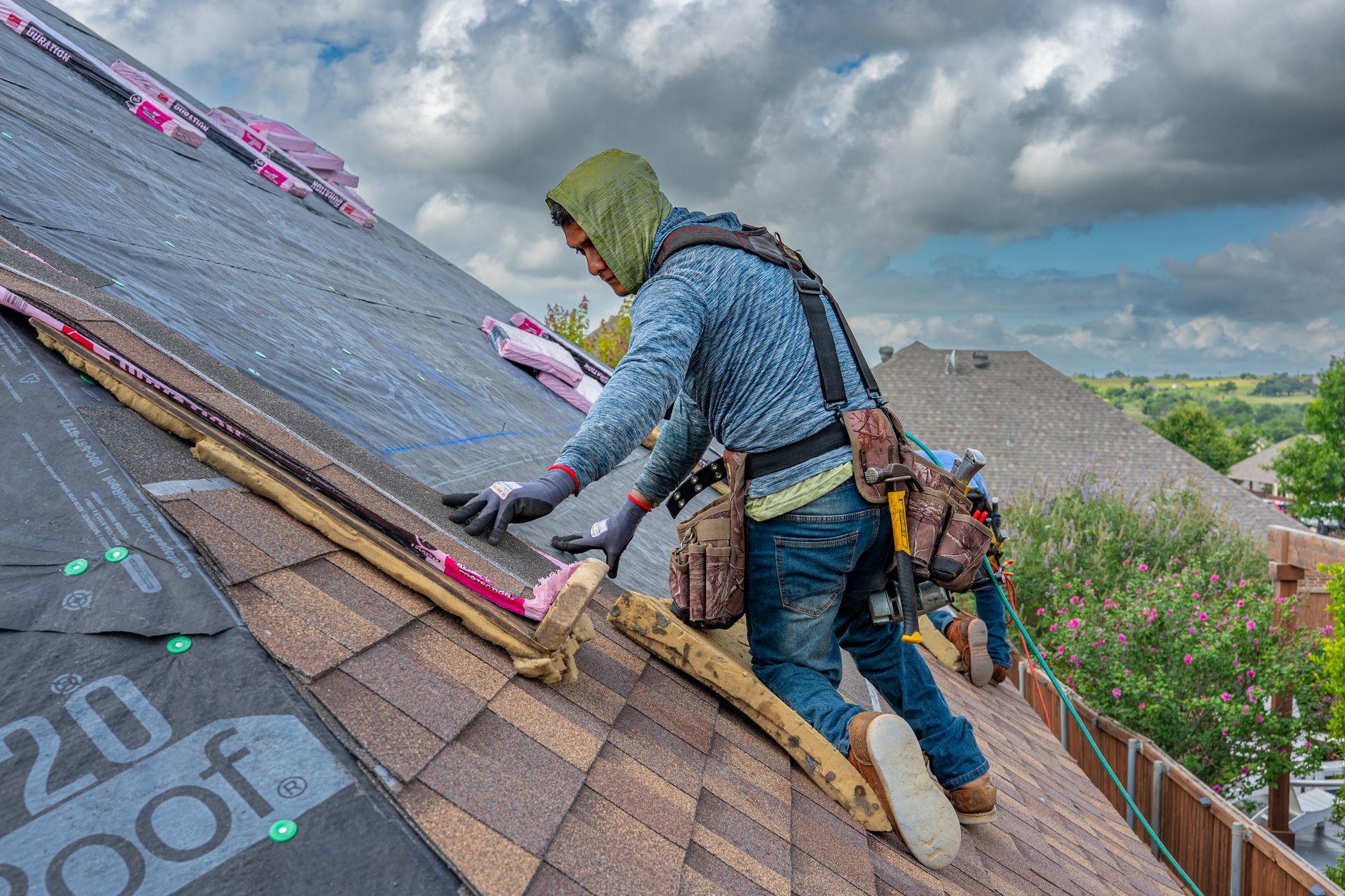 Professional roofers installing asphalt shingles on a residential roof